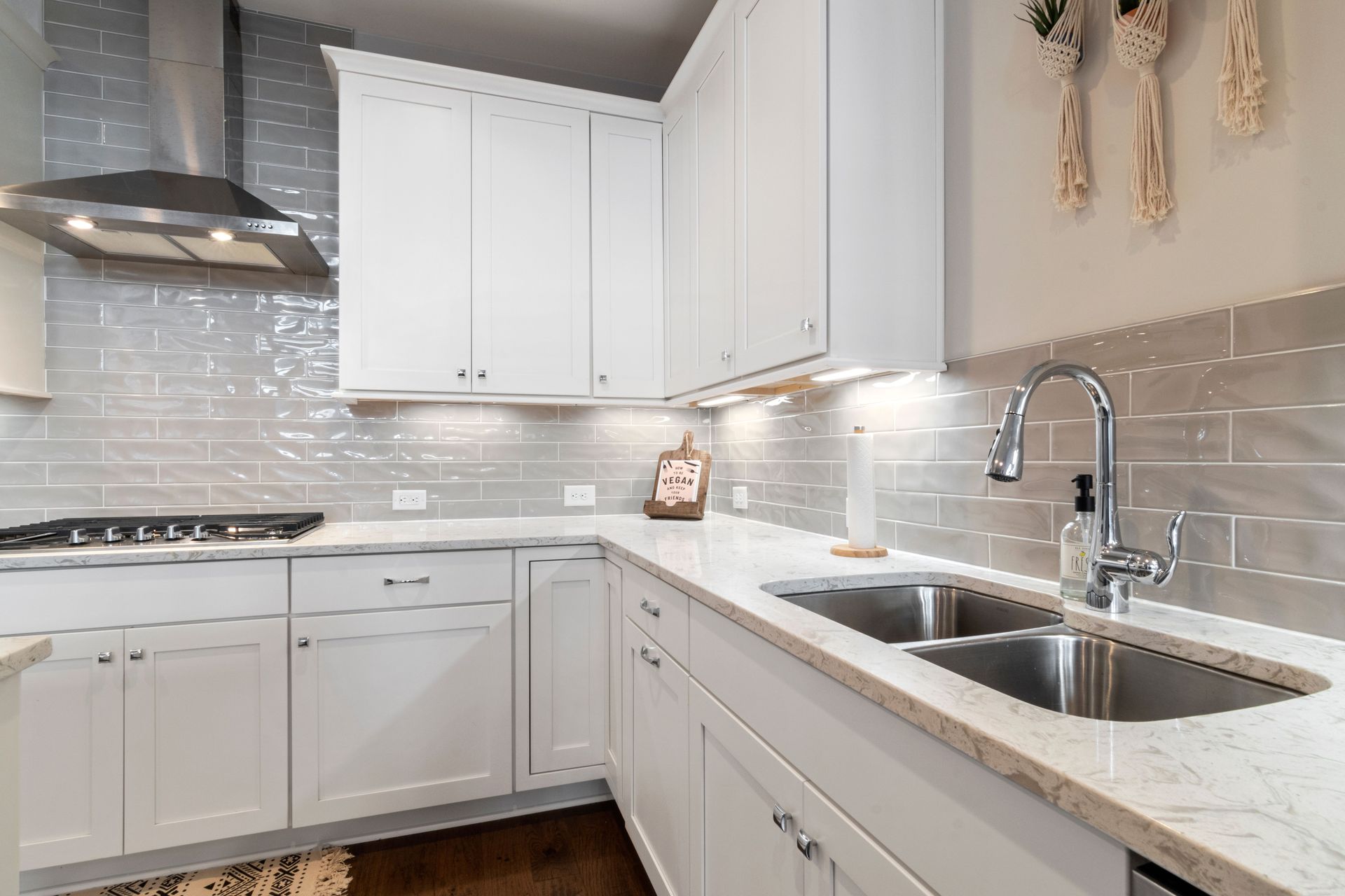 Sleek white kitchen with marble countertops and modern fixtures.